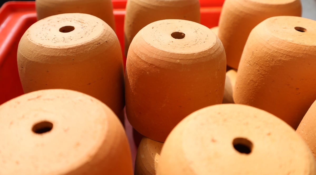 Close-up of numerous terracotta pots with drainage holes stacked upside down. The pots are small, rounded, and smooth.